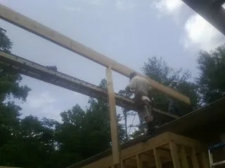Carpenter setting a ridge beam over a new addition frame — Ice Dam Removal by Roofing Brothers in Milner