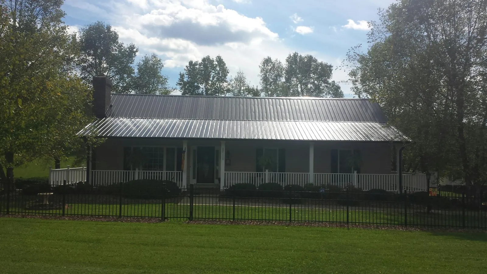 Gray metal roof on a brick ranch with a full width front porch — Gutter Guard Installation work by our crew in Milner